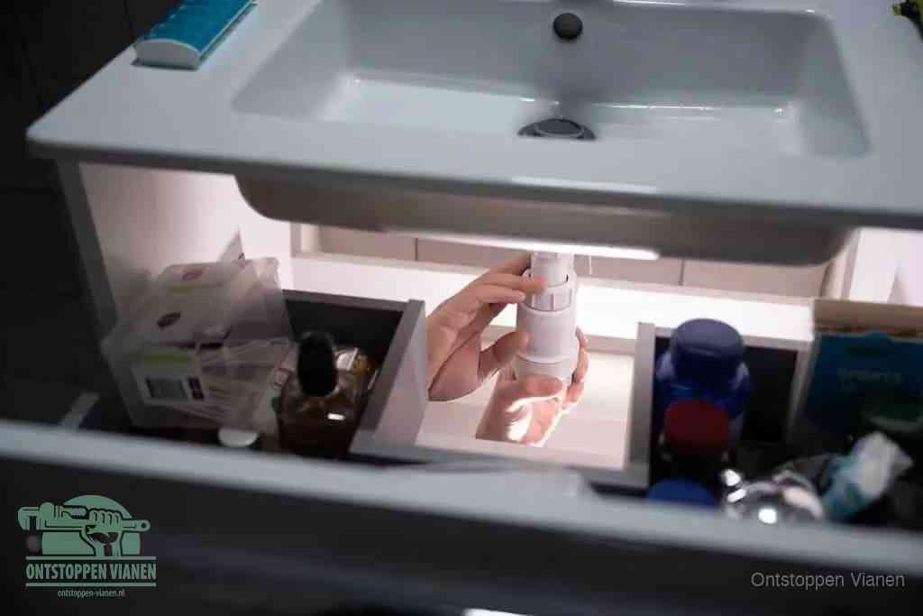 Een pompfles met zeep boven een wastafel, de heet water en afwasmiddel-methode om een vetprop in de afvoer los te maken in Vianen