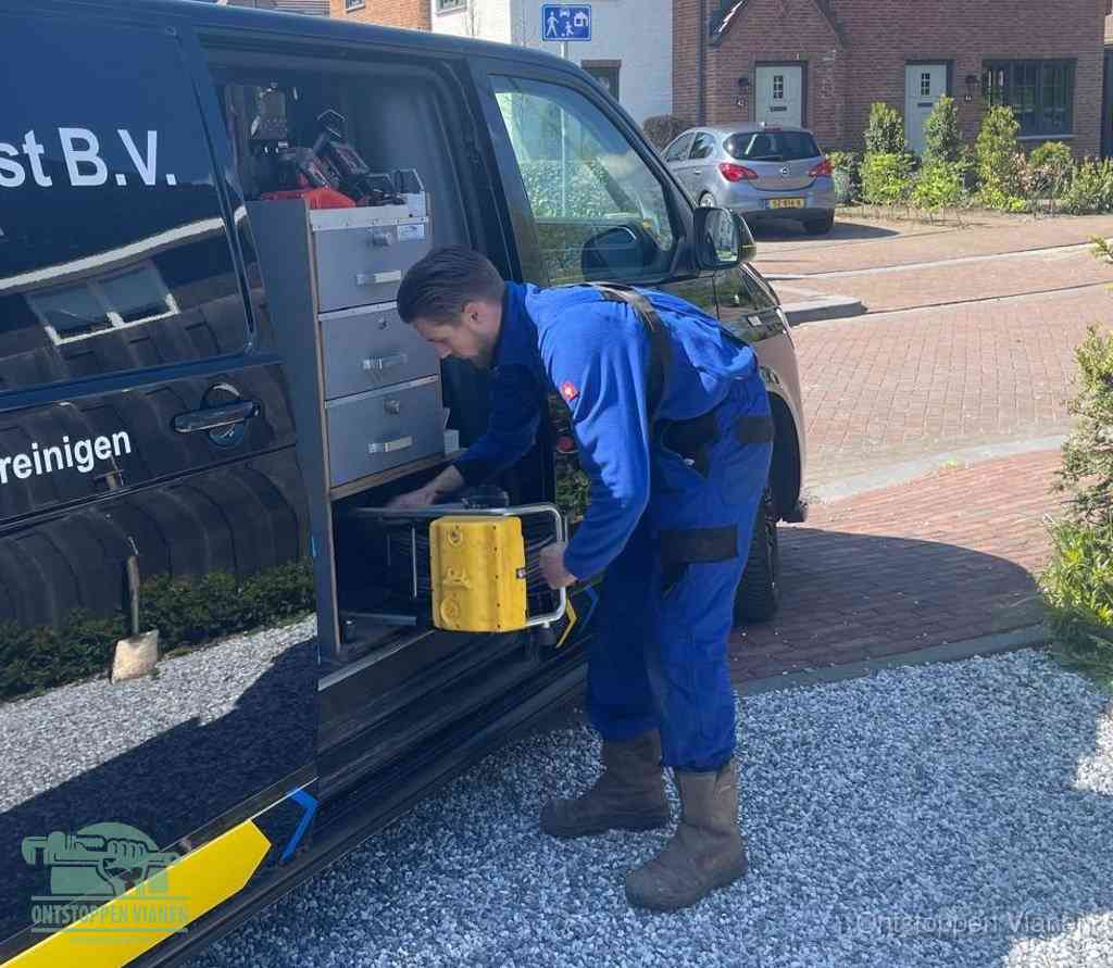 Een monteur pakt buiten op de oprit gereedschap uit de bedrijfsbus, het moment om een professional in te schakelen voor een verstopte afvoer in Vianen