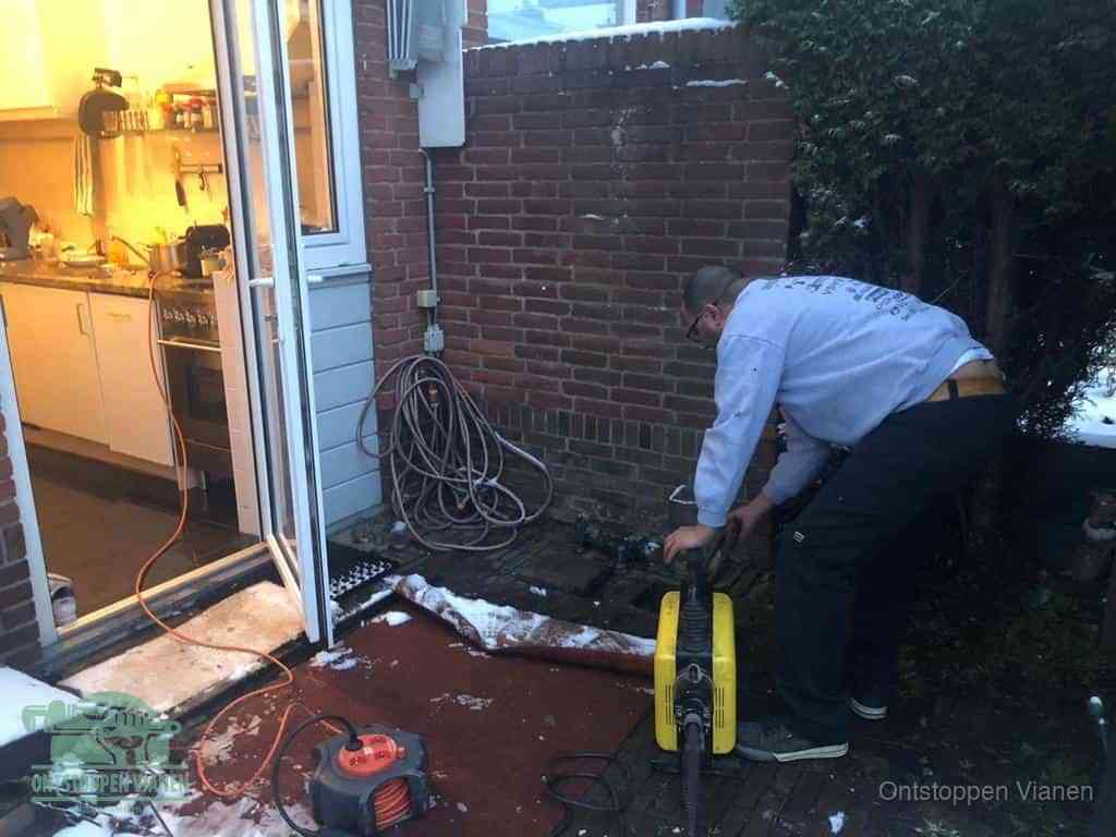 Een monteur werkt buiten bij een open riool-/grondput met een elektrische ontstoppingsmachine om een verborgen afvoerprobleem op te sporen in Vianen