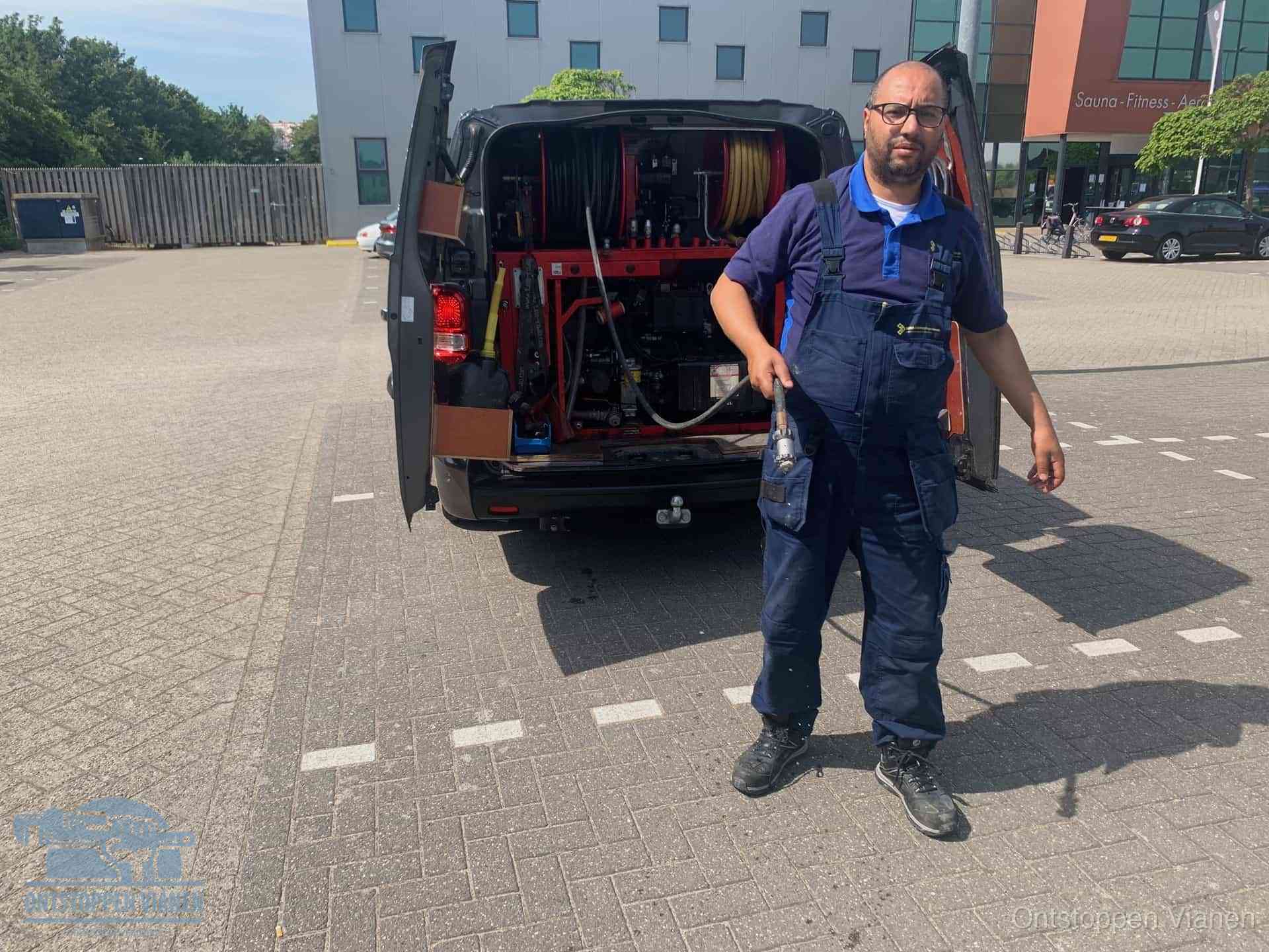 Een monteur bij zijn bestelbus met een hogedruk- en rioolreinigingsunit, klaar om de oorzaak van terugkerende wc-verstoppingen aan te pakken in Vianen