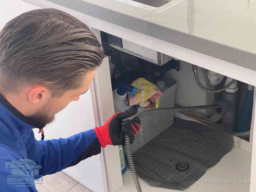 Een monteur voert een flexibele ontstoppingsveer in de afvoer om een verstopping voorbij de bocht van het toilet te bereiken in Vianen