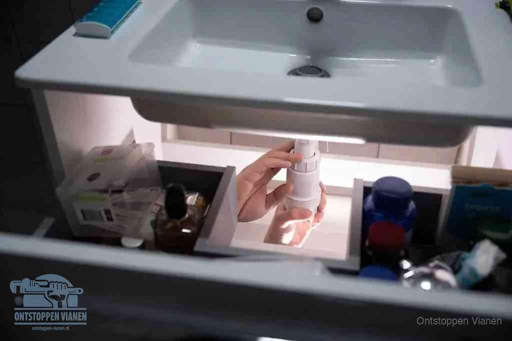 Een pompfles met zeep boven een wastafel in de toiletruimte, de warm water en afwasmiddel-methode om de wc te ontstoppen in Vianen