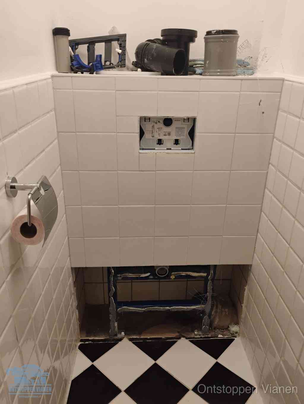 Een toiletruimte waar het hangtoilet en de inbouwreservoir-onderdelen zijn vrijgelegd voor onderhoud, periodiek nazicht voorkomt een wc-verstopping in Vianen