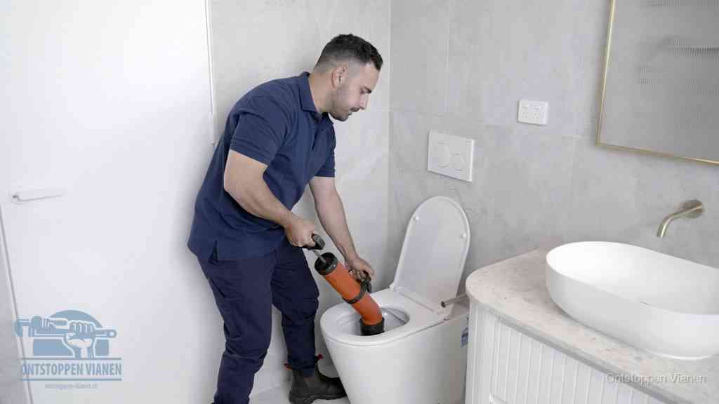 Een monteur gebruikt een handmatige perspomp (toiletontstopper) op een wandcloset tijdens het professioneel wc ontstoppen in Vianen